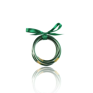 Dettaglio di bracciali in resina verde scuro glitterati con fiocco decorativo