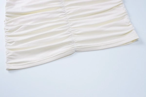 Dettaglio macro del tessuto arricciato bianco crema sul vestito aderente con cuciture fini