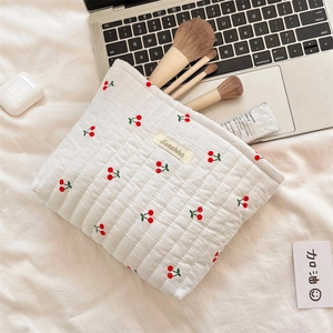 Close-up of quilted cherry print toiletry bag with makeup brushes inside
