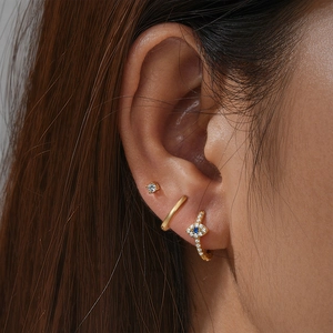 Detailed view of 3-piece gold S925 silver evil eye earring set worn by a model