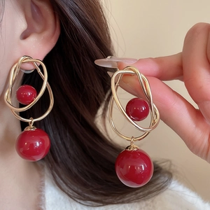 Detail of red glazed beads and twisted gold wire earrings on person for size view