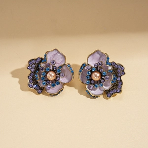 Détail de boucles d'oreilles fleur vintage avec émail violet, cristaux et perles