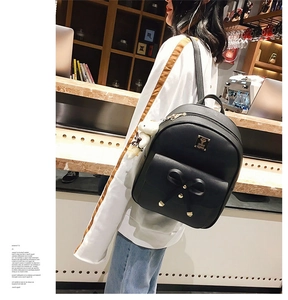 Detail shot of black PU leather backpack with bow pocket and cute white bear keychain accessory