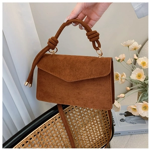 Detail of a brown suede handbag with a unique knotted handle and elegant gold hardware