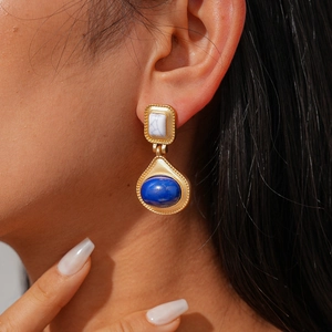 Nahaufnahme der Vintage-Ohrringe in Gold mit weißem Stein und blauem Edelstein am Model