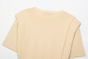 Detail of overlapping shoulder structure and ribbed crew neck on beige knit crop top