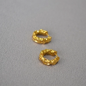 Detail shot of golden hoop earrings with irregular lava texture and hammered finish