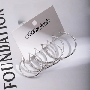 Three pairs of minimalist silver hoop earrings in different sizes on a white display card
