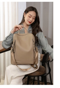 Detail of khaki PU leather backpack showing multi-zipper compartments and rivet accents