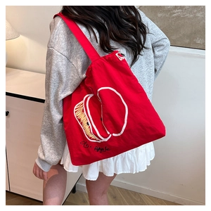 Detailed view of the red nylon drawstring tote bag with white apple graphic and text
