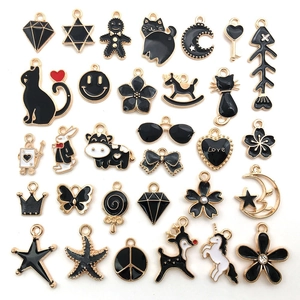 Flat lay of black and gold enamel charms featuring animals, stars, and moon shapes