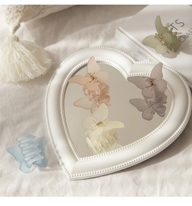 Macro view of matte butterfly hair claws in pastel colors on a heart shaped mirror