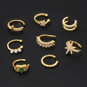Set of 8 gold ear cuffs featuring pearls and star zirconias on a dark background