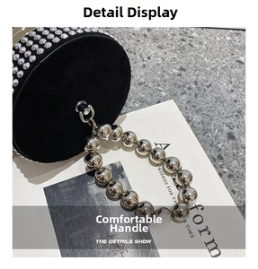 Detail view of black round handbag with metallic studs and large silver bead handle chain