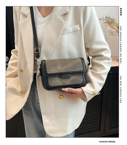 Detail of minimalist leather crossbody bag showing dual-tone texture and strap hardware