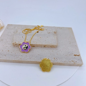 Close-up of golden cherry blossom pendant with purple enamel and yin yang symbol detail
