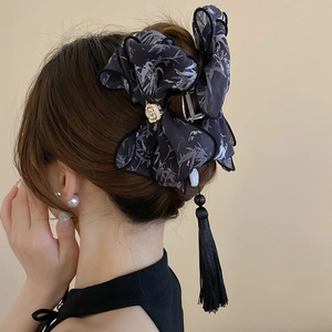 Détail d'une pince à cheveux noire avec imprimé bambou et longues franges en soie