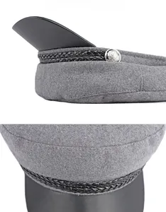 Detail of wool baker boy hat with braided trim, metallic button and faux leather visor