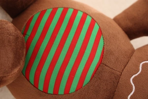 Close-up of plush Christmas toy showing striped red and green fabric with embroidery detail