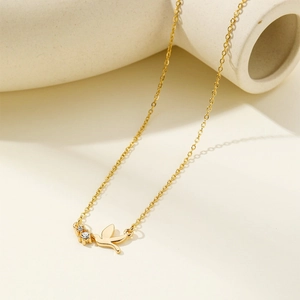 18K gold plated stainless steel bird necklace with diamonds shown on ceramic background