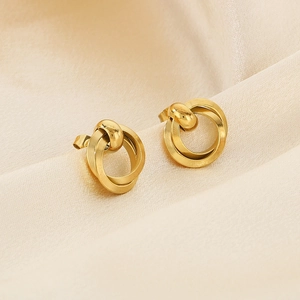 Elegant gold-tone geometric intertwined hoop earrings on champagne silk background