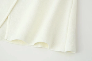 Detailaufnahme der cremefarbenen Strickjacke mit weicher Textur und feinem Saumdesign