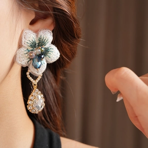 Gros plan détaillé de boucles d'oreilles en dentelle vintage avec perles et pierre en goutte