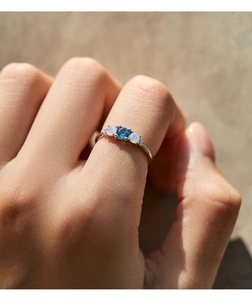 Detailed macro shot of an S925 silver ring featuring blue topaz and iridescent opals