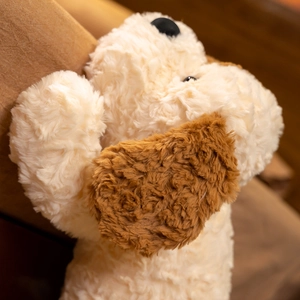 Close-up detail of soft cream and brown plush puppy dog toy with curly fur