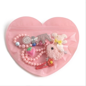 Pink heart-shaped jewelry pouch containing assorted colorful children accessories