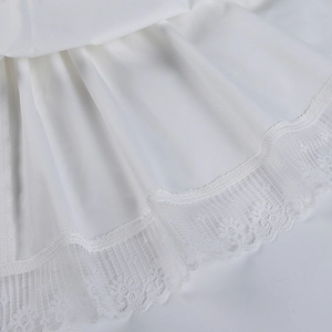 Detalle del dobladillo de encaje blanco y tela plisada en un vestido de verano