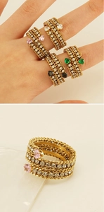 Detail of layered gold chain rings with heart stones in pink white green and black