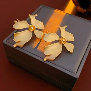 Detail of matte gold vintage flower earrings with stamen design on a jewelry box