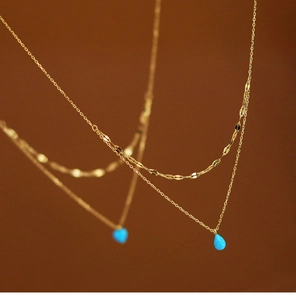 Detailed macro view of vibrant blue teardrop opal pendant on layered 18K gold plated chain