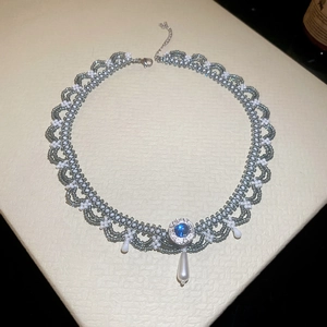 Detailed macro of beaded choker with blue gemstone and hanging pearl pendants
