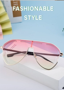 Detail view of fashionable oversized sunglasses with pink gradient lenses on a display stand