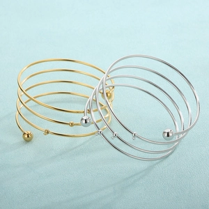 Spiral 18K gold and silver multi-layer bangles with polished bead accents on blue texture