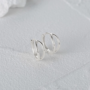 Detailed view of minimalist S925 sterling silver hoop earrings on a grey stone texture