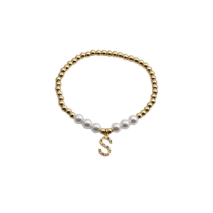 Gold beaded pearl bracelet with a colorful gemstone letter S charm on a white background