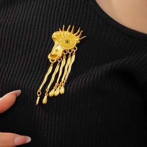 Detail of vintage surrealist golden eye brooch with fringe on black sweater