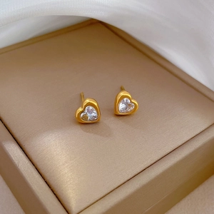 Detail shot of heart-shaped gold stud earrings with white zircon in a champagne box