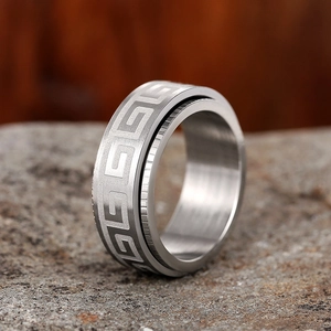 Macro detail of silver stainless steel spinner ring with Greek key pattern on stone