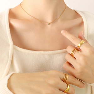 Elegant gold necklace with zircon pendant and stacked rings on a female model