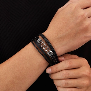 Detail of multi-layer black braided leather bracelet with silver cross metal buckle
