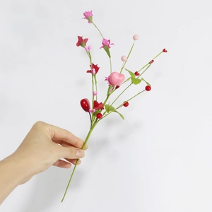 Detail of hand-held decorative branches with red heart-shaped berries and pink paper flowers