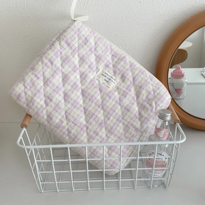 Quilted plaid makeup bag with pink and yellow checks stored in a metal basket