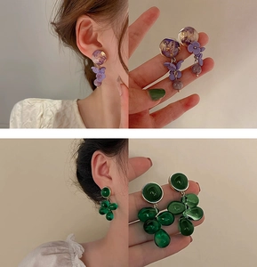 Detail view of long beaded flower and pearl tassel earrings in purple and green colors