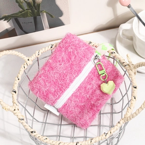 Vibrant pink fuzzy coin purse with heart pendant displayed in a woven basket setting