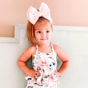 Close-up of baby floral camisole top and oversized pink bow headband accessory