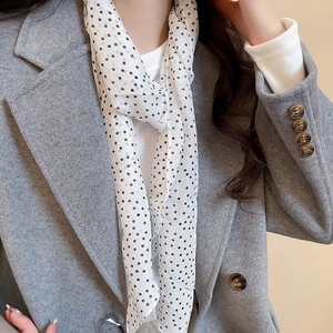 Detailed shot of a black polka dot fabric scarf necklace paired with a wool coat
